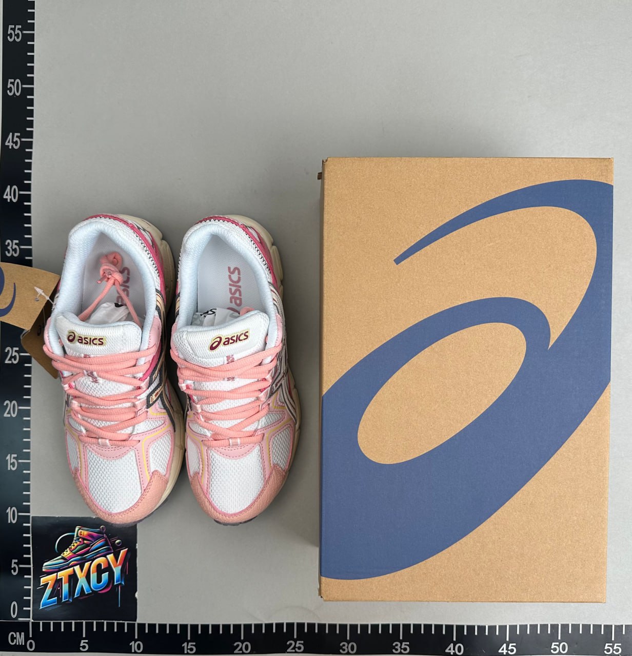 Pink and white shoes shown beside their box in a warehouse QC photo