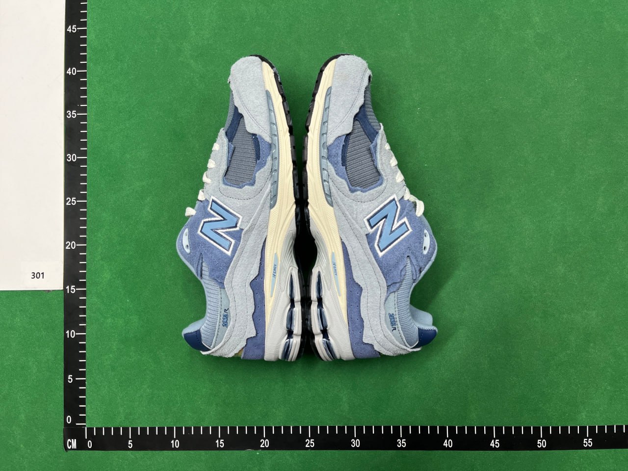 Pair of blue shoes placed heel-to-toe against a warehouse measurement board